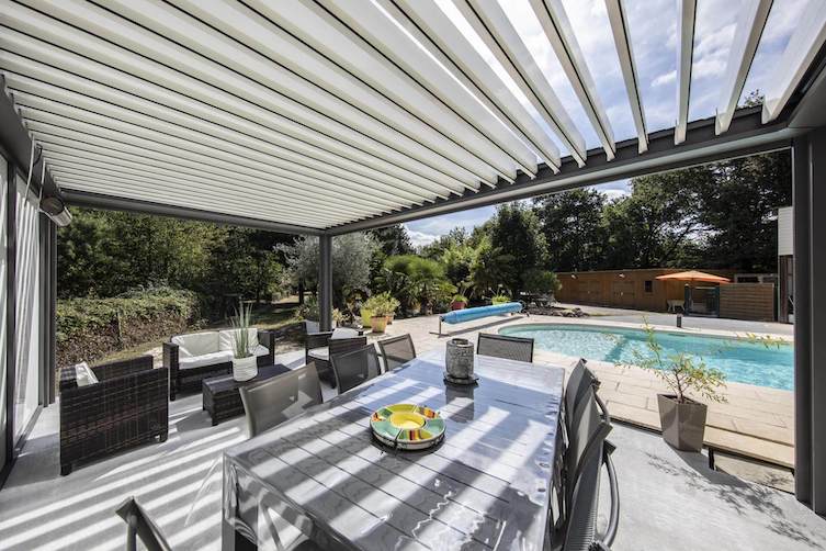 Pergolas Bio-climatique abritant un salon de jardin devant une piscine