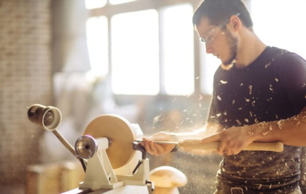 Menuisier scultant uen pièce de bois à l'aide d'un tour à bois