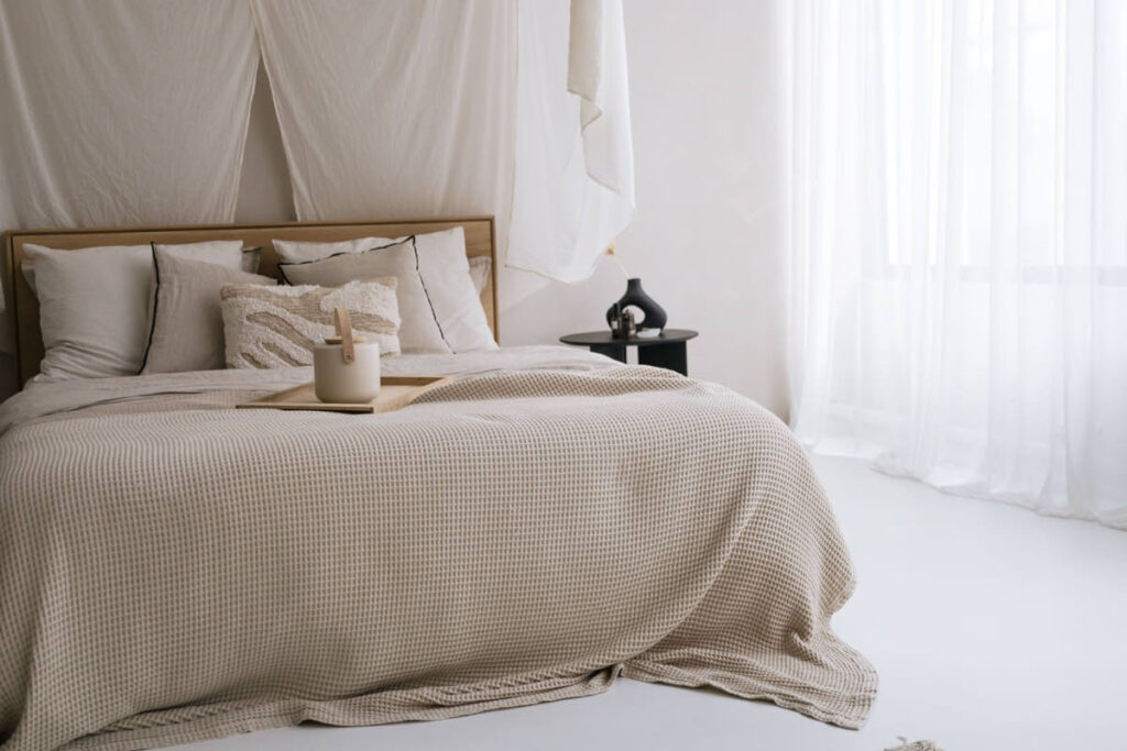 inge de lit en lin, plaid en laine et bois clair créant une atmosphère cocon dans la chambre